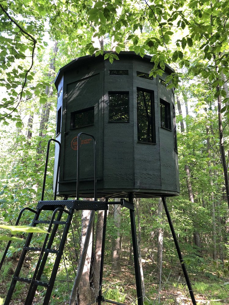 360 Pro hunting blind on a tower stand with a ladder, tucked into green woods