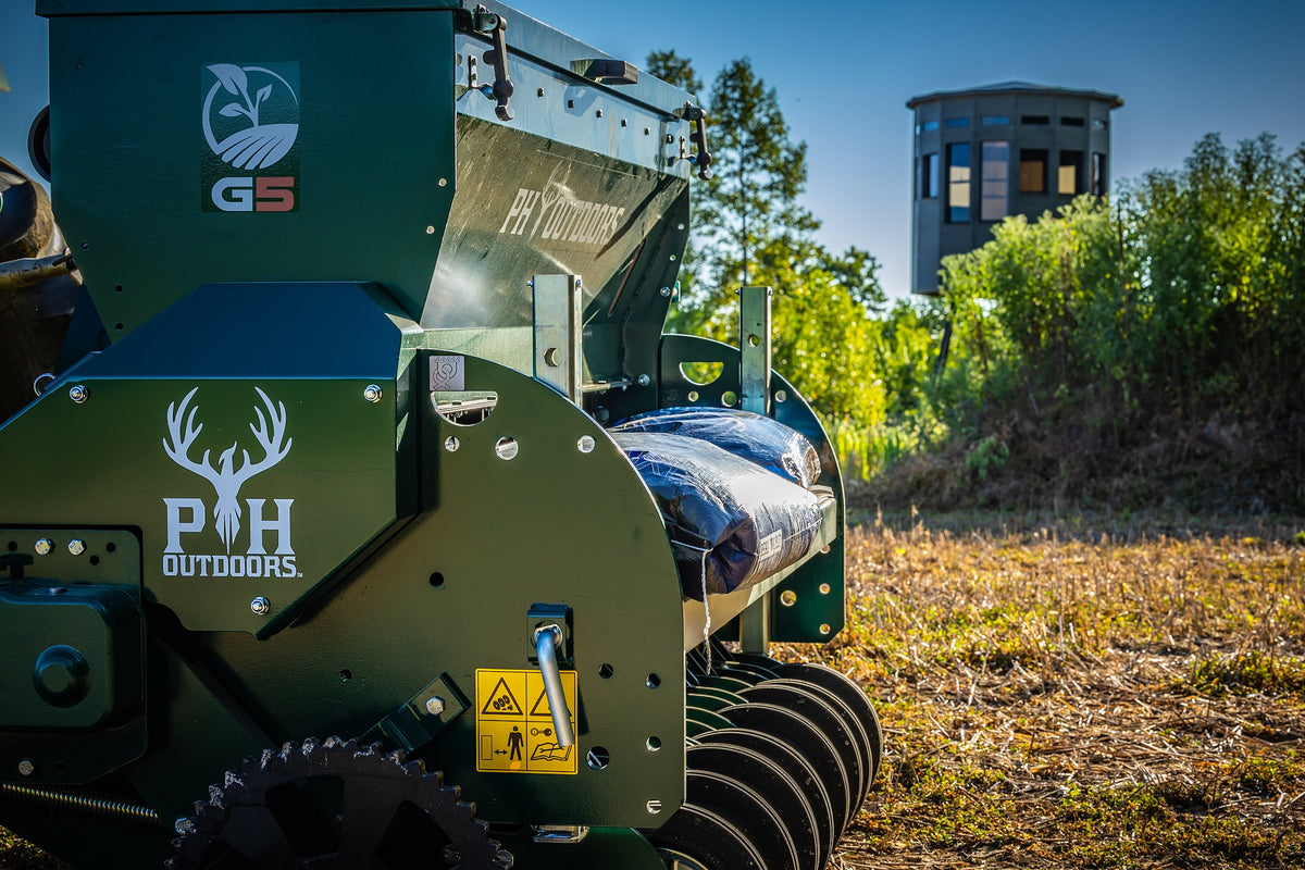 A PH Outdoors G5 food plot planter working a field, with a 360 hunting blind elevated on a tower stand in the background