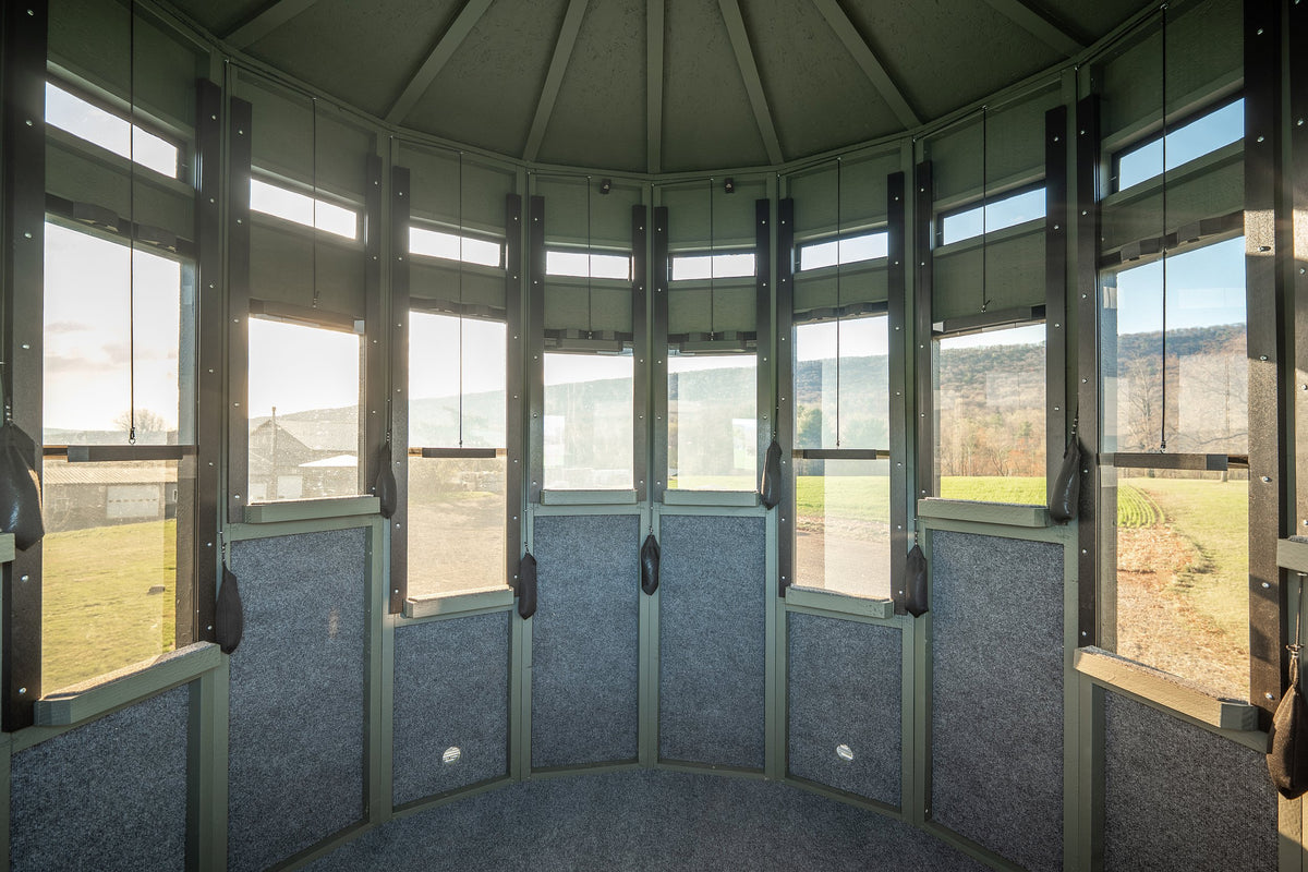 Interior of a 360 Pro XL hunting blind showing padded walls and wraparound windows overlooking a valley
